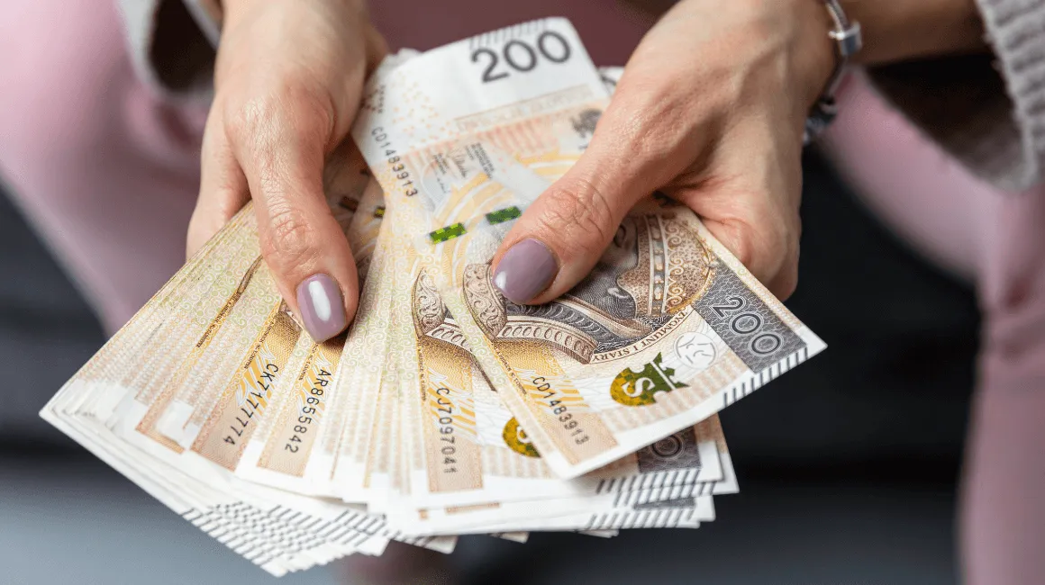 Kobieta trzyma w dłoniach plik banknotów 200 złotowych